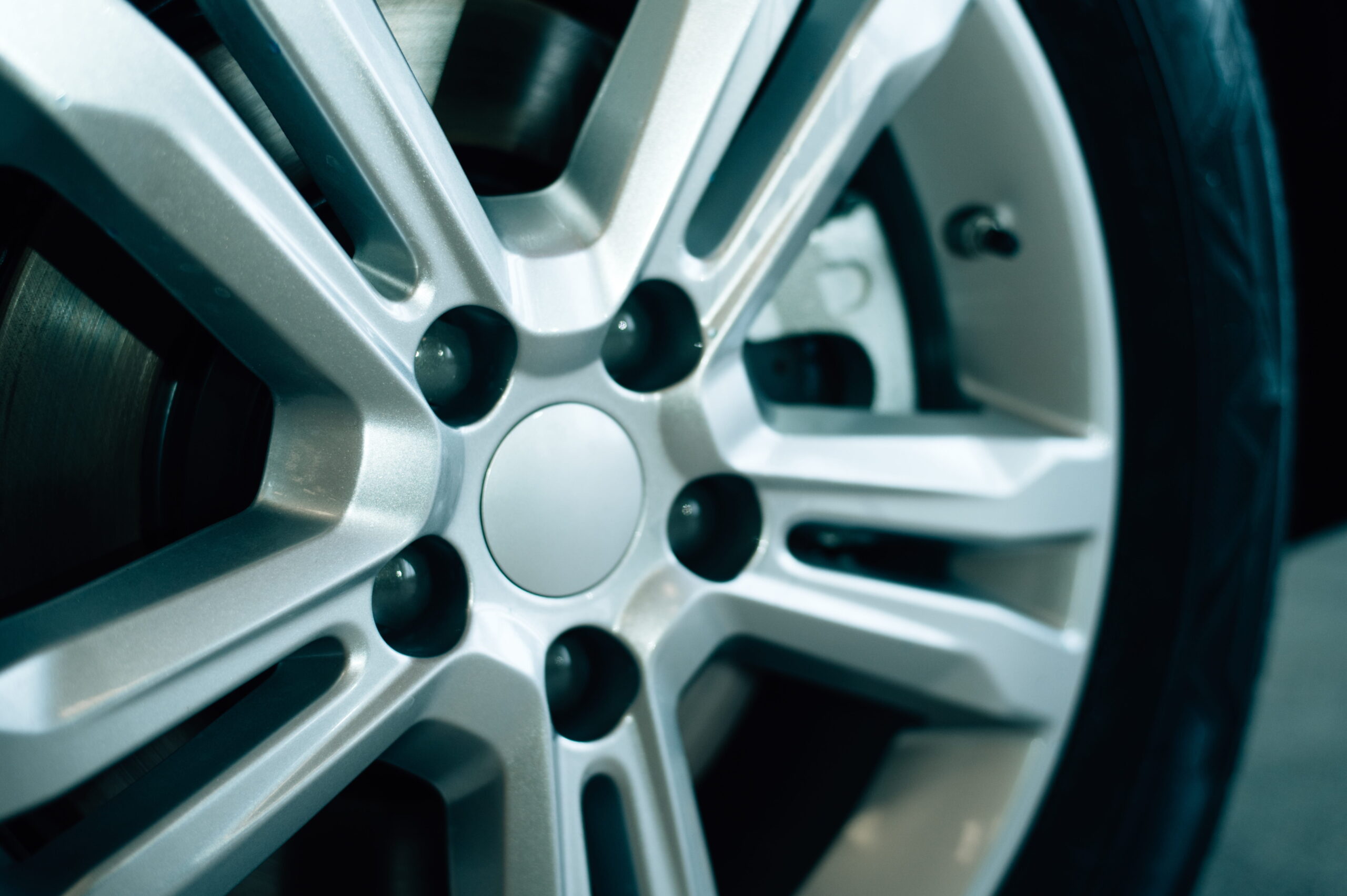 Close-up of a sleek, modern silver alloy wheel with intricate spoke design, highlighting the metallic sheen and detail. The tone is polished and sophisticated.