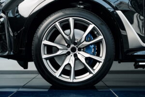 Close-up of a car's alloy wheel with a sleek, modern design. The wheel features a visible blue brake caliper, reflecting a high-performance aesthetic.