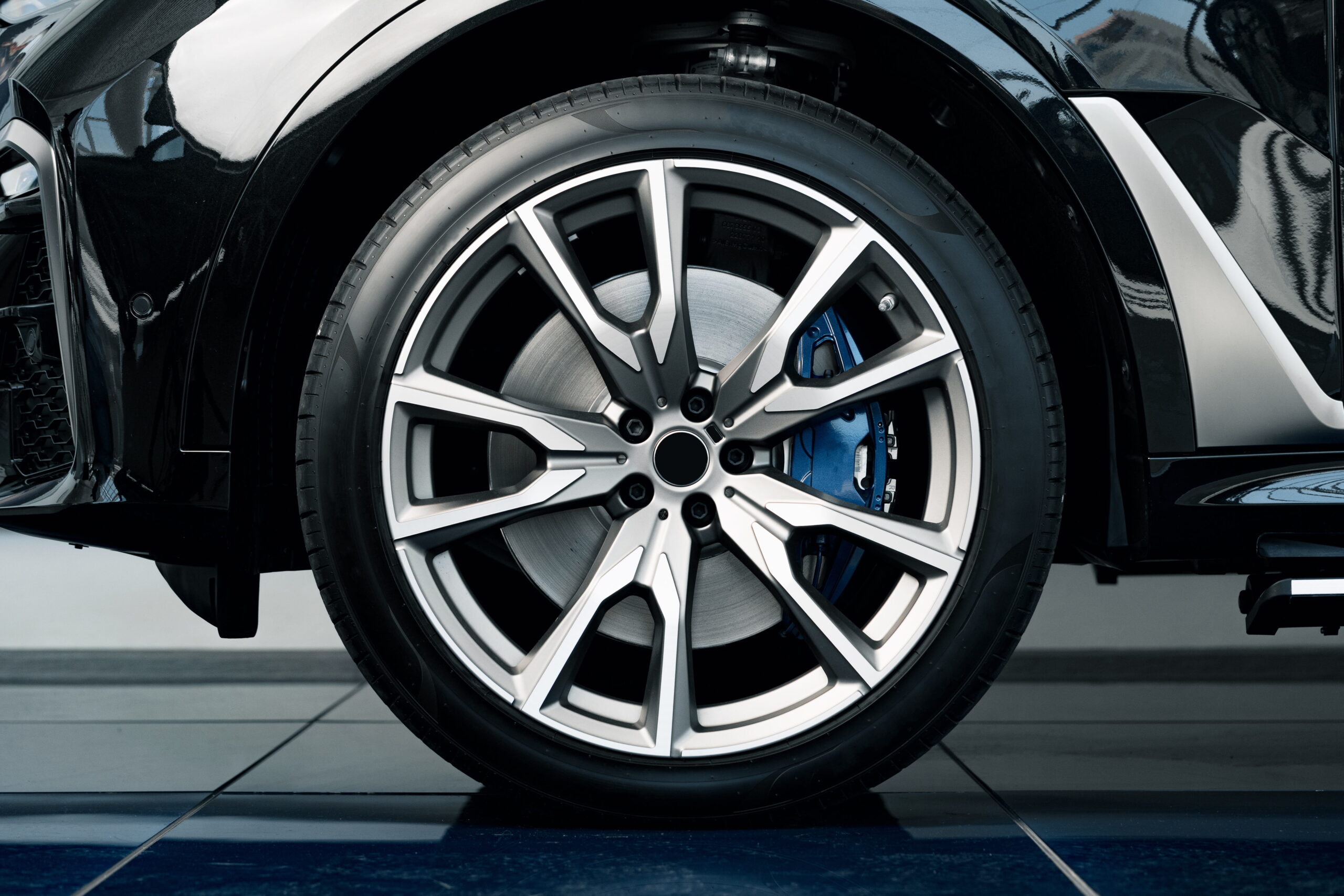 Close-up of a car's alloy wheel with a sleek, modern design. The wheel features a visible blue brake caliper, reflecting a high-performance aesthetic.